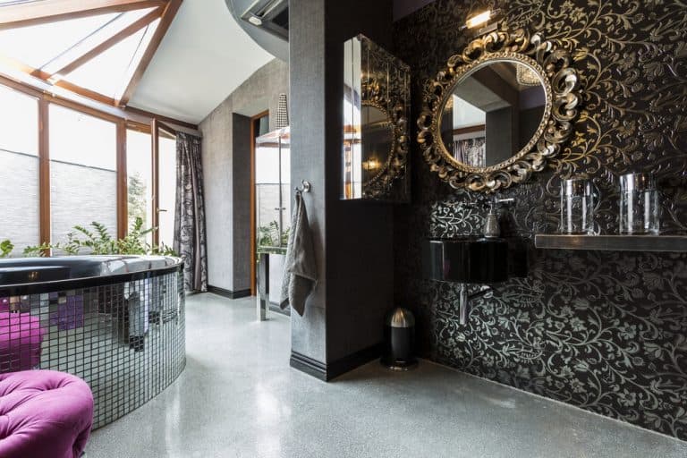 Very luxurious futuristic dark bathroom with mosaic tilted bathtub with balcony and partially glass roof